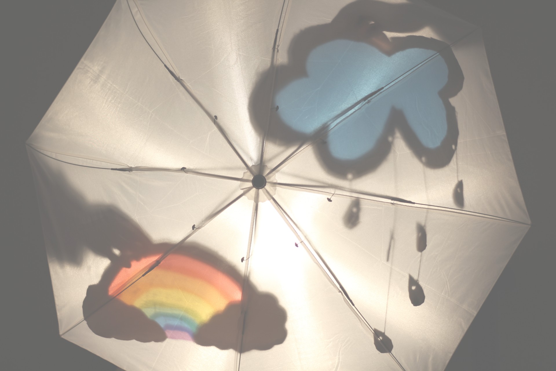 An umbrella with a rainbow and cloud design.