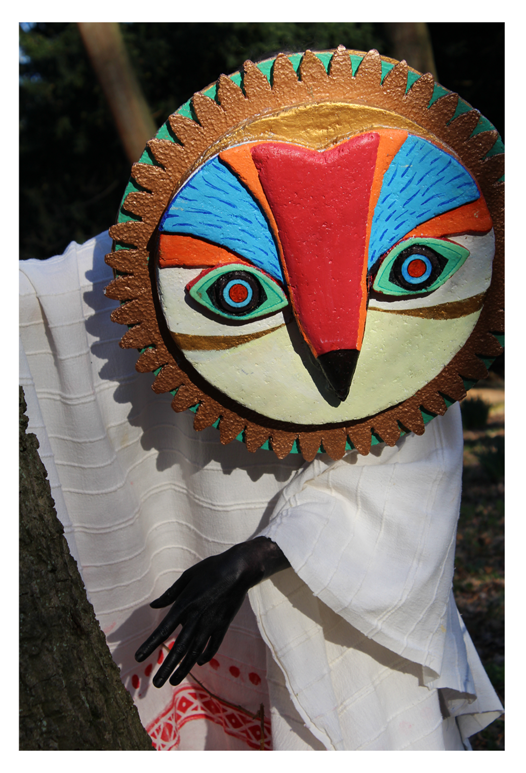 An owl mask made from recycled materials (cardboard and packaging polystyrene) painted with acrylic, and a poncho made from recycled cloth.